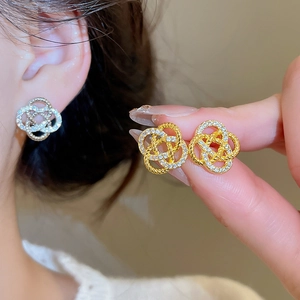 Détail macro de boucles d'oreilles nœud dorées avec zircons portées par un mannequin