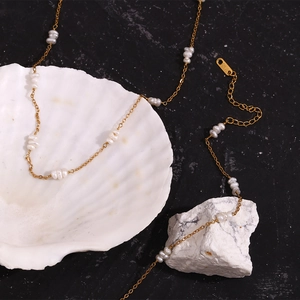Détail d'un collier en or 18 carats avec perles blanches sur un coquillage naturel et pierre