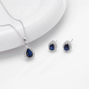 Macro shot of silver jewelry set featuring blue teardrop pendant and stud earrings