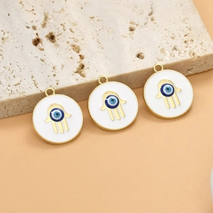 Detailed view of Hamsa Hand and Evil Eye pendants on beige stone background