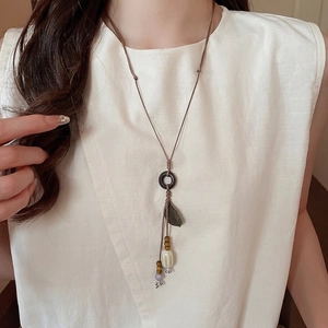 Bohemian ceramic wood bead long pendant necklace with leaf charm on white linen shirt