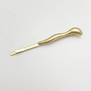 Detailed view of a wave-shaped golden alloy hair clip with a smooth metallic finish