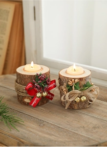 Close-up of wooden Christmas candle holders with rustic bark, red ribbons and tea lights