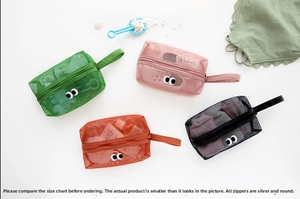 Detail of four mesh organizer bags with cartoon eyes and portable handles in various colors