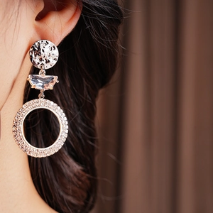Close-up of three-tier gold earrings with crystal and rhinestone circles on model