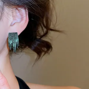 Layered C-shaped emerald green zircon stud earrings with fringe design on female model