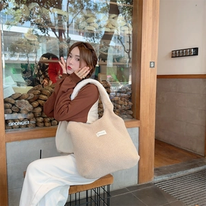 Detailed view of beige plush fleece tote bag with woven label in warm lifestyle setting