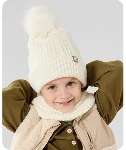 Close-up of kids winter knit hat and scarf set featuring a fluffy faux fur pompom decoration