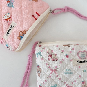Close-up of quilted floral coin purses with cute bear and rabbit prints in pink and cream
