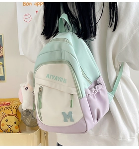 Back view of a girl wearing a color-block mint green and purple school backpack