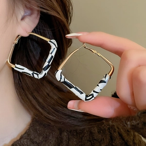 Detail shot of golden square hoop earrings featuring stylish black and white zebra print textures