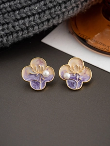 Detail of four-leaf clover earrings with purple enamel petals and central natural pearl