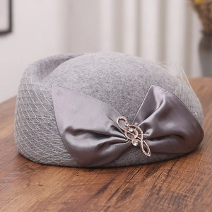 Detailed macro view of gray wool beret with satin bow, musical note pin and mesh veil
