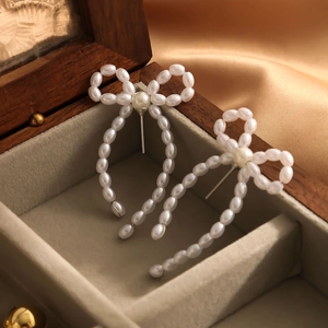 Macro shot of pearl woven bow earrings with elegant fringe detail in a luxury jewelry box