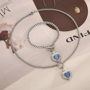 Détail d'un ensemble de bijoux en acier argenté avec opales coeur bleu sur un magazine