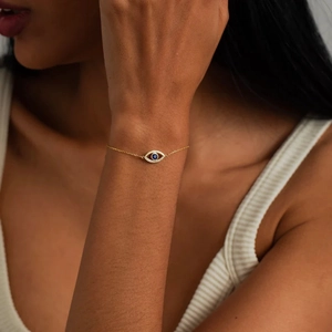 Close-up of a gold evil eye bracelet with blue stones on a female wrist detail