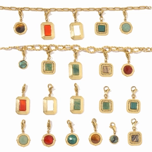 Macro shot of geometric gold pendants with colorful gemstones on a chunky chain