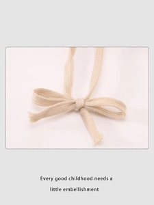 Detail showing off-white cotton woven tie and bow decoration on winter warm hat