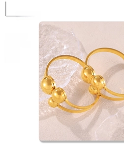 Detail of a minimalist gold spring cuff bracelet with polished beads on a stone base