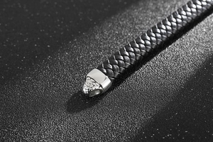 Vue macro du cuir noir tressé et du fermoir magnétique en acier inoxydable argenté
