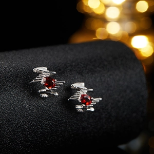 Macro shot of silver earrings with red oval gemstones on a black display stand