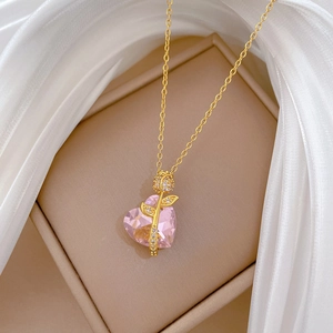 Detail of pink heart crystal necklace with gold rose and zircon inlay on jewelry box