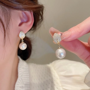 Detailed view of gold plated earrings featuring sparkling leaves and a drop pearl