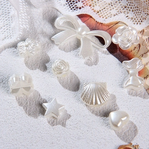 Macro shot of white baroque faux pearl charms in heart, shell, and bow shapes