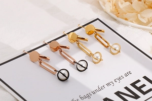 Close-up of long drop pearl earrings in gold, rose gold and black titanium steel finishes