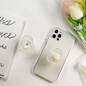 Detailed view of floral resin and pearl phone grips on a smartphone for desk support