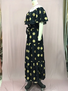 Detail eines schulterfreien schwarzen Maxikleids mit eleganten goldenen Punkten und Taillengürtel