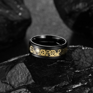Détail macro de la bague en titane noir avec engrenages mécaniques dorés sur roche