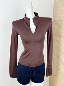 Detail of a brown slim fit long sleeve yoga top featuring a stand collar and half-zipper