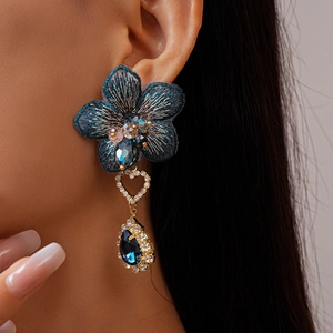 Gros plan sur les boucles d'oreilles fleurs brodées bleues avec strass et détails dorés