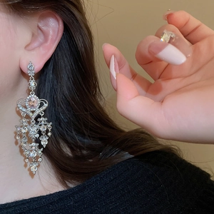 Detailed view of silver chandelier tassel earrings with glittering rhinestones on model