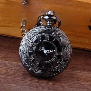 Macro shot of large black vintage pocket watch with intricate floral engravings and Roman numerals