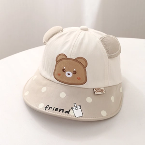 Détail d'un chapeau de soleil bébé avec ours brodé, oreilles 3D et bord à pois blancs