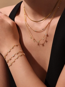 Détail d'un ensemble collier et bracelet multi-rangs plaqué or 18K avec breloques MAMA