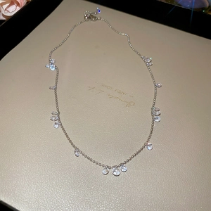 Detailed macro view of silver bead chain necklace with bezel-set clear zircon crystals