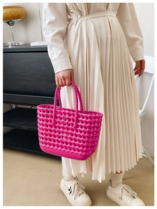 Close-up of a pink hollow-out woven jelly tote bag held by a model for beach holidays