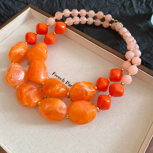 Detail of double-layer beaded necklace featuring orange marble and pink resin beads