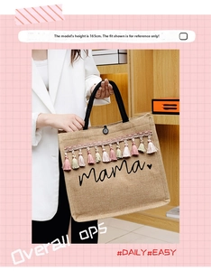 Detail of jute tote bag with 'mama' print and colorful tassels held by a model