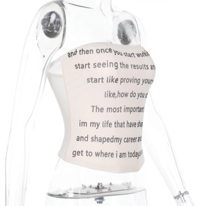 Detail eines schmal geschnittenen cremefarbenen Bandeau-Tops mit schwarzem Buchstabendruck