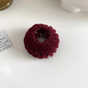 Detailed view of the burgundy velvet bird nest hair clip with plush flocked texture