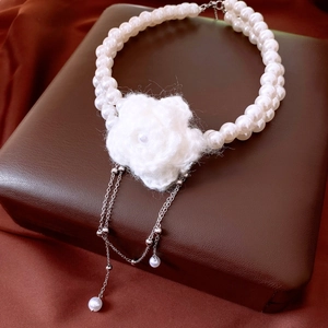 Macro shot of double-layer pearl necklace with a white knit flower and silver tassels