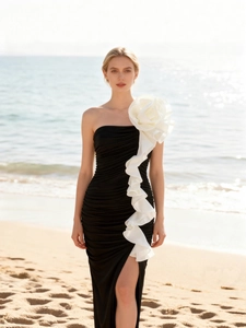 Elegant black strapless fishtail dress with a large white floral ruffle on beach background