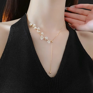 Close-up of gold-plated Y-necklace featuring floral accents and elegant pearl charms