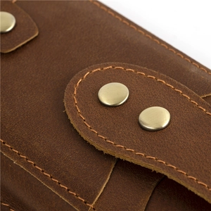 Detailed close-up of dark brown crazy horse leather with vintage rivets and stitching
