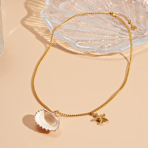 Detail of gold starfish and shell pendants on a refined beach style necklace