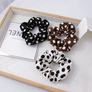 Vue détaillée de trois chouchous tricotés à pois en noir, marron et blanc cassé